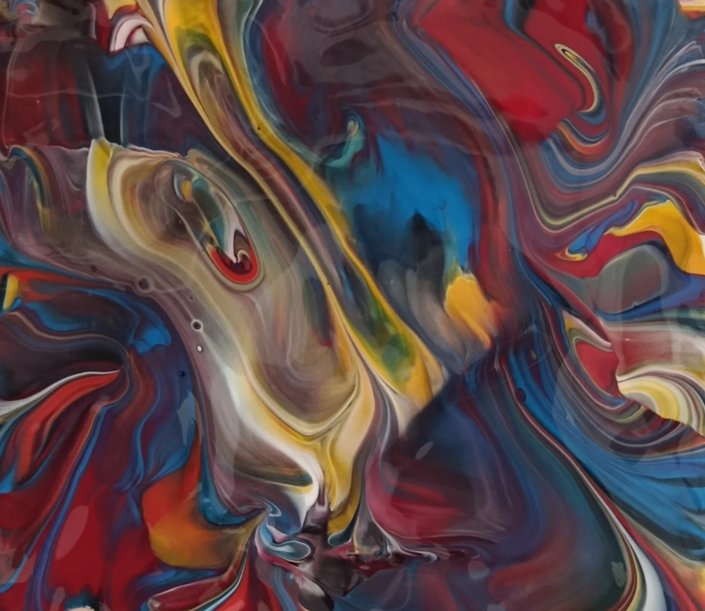 Abstract fluid painting with swirling red, blue and yellow paint